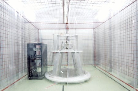 Industrial equipment behind a plastic sheet shown in florescent lighting at medium distance.
