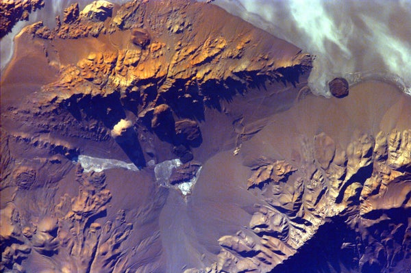 Aerila view of Jagged snow-covered peaks across a barren, rocky landscape