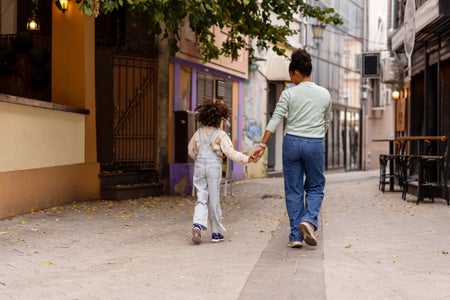 Joyful Black Mother and Little Girl Bonding While Walking Side by Side