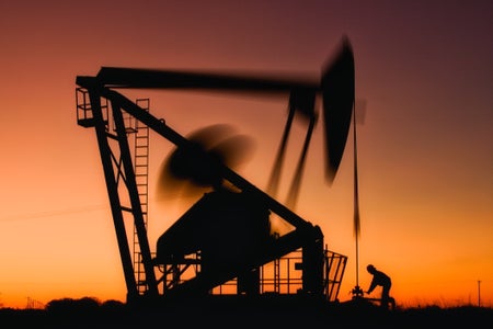 Oil Field Worker and Pumping Wellhead.