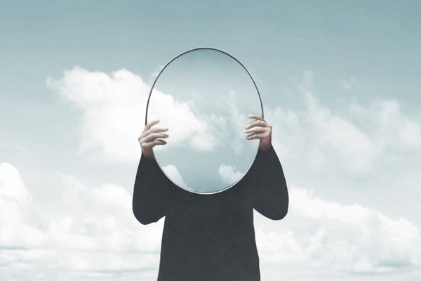 Man holding mirror in front of face