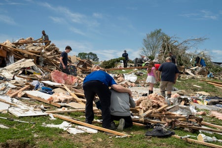 Man kneeling in front of his destroyed home.